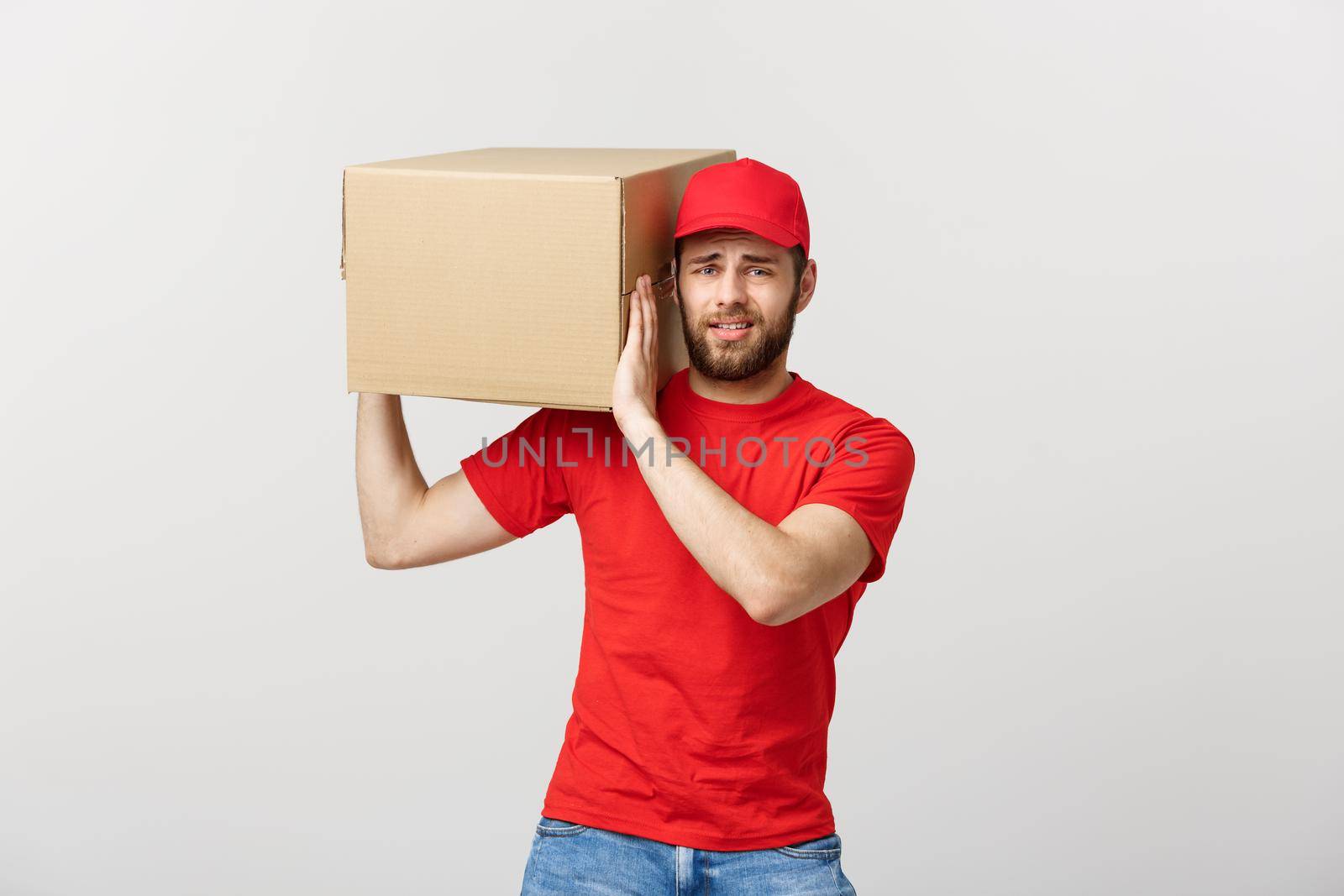 Delivery Concept: handsome Delivery man with boxes, delivery, courier with worry facial expression. Isolated grey background