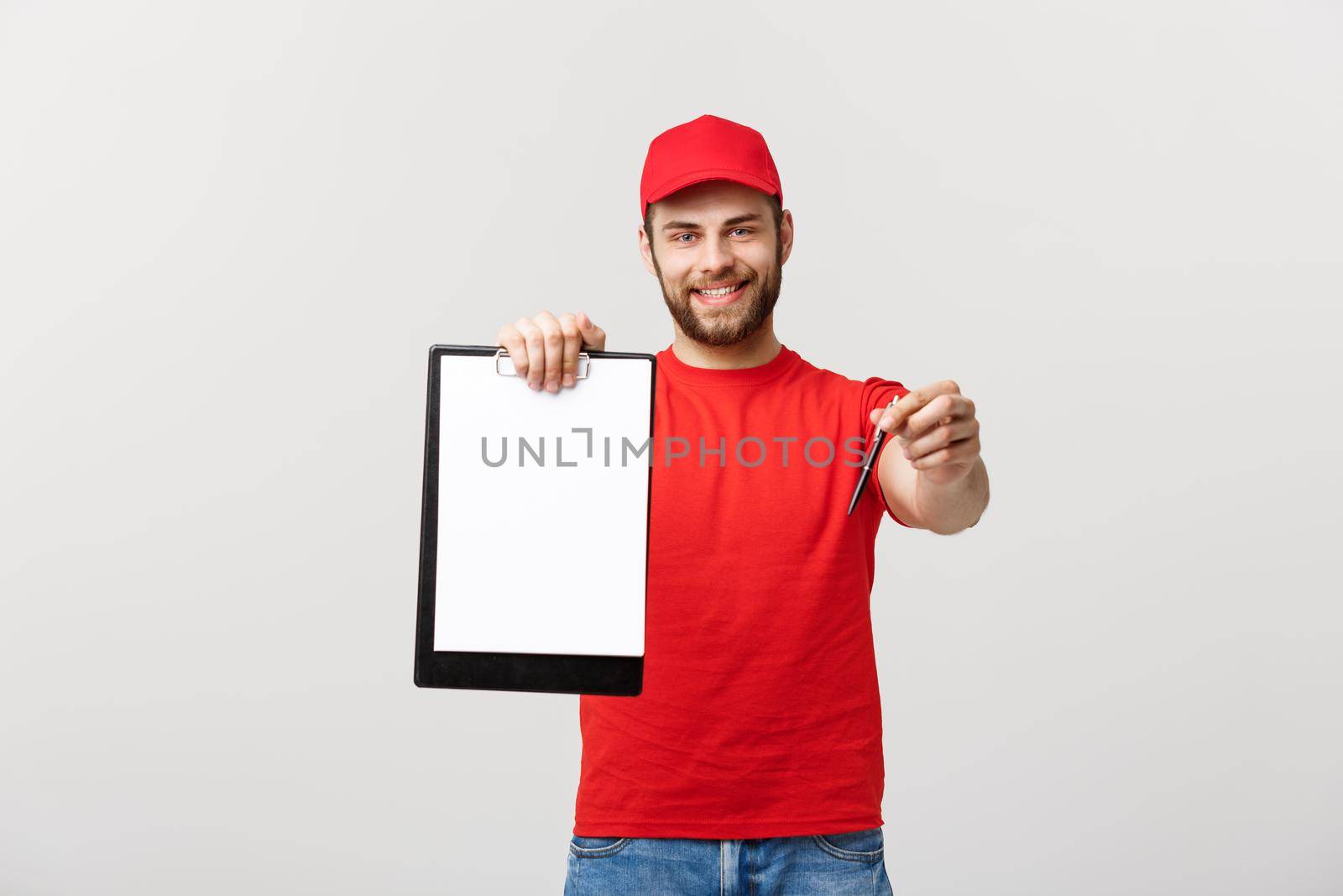 Delivery Concept: Portrait Young caucasian Handsome delivery man or courier showing a confirmation document form to sign. Isolated on Grey studio Background. Copy Space