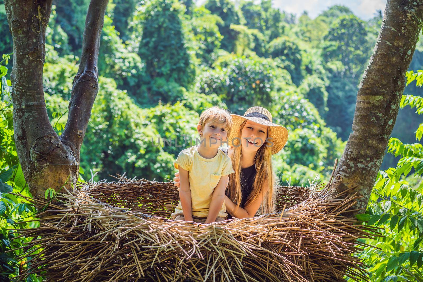 Bali trend, straw nests everywhere. Happy family enjoying their travel around Bali island, Indonesia. Making a stop on a beautiful hill. Photo in a straw nest, natural environment. Lifestyle. Traveling with kids concept. What to do with children. Child friendly place.