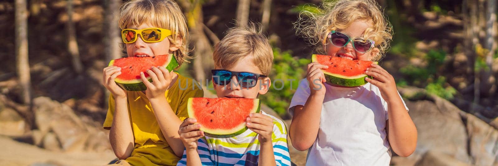 Children eat watermelon on the beach in sunglasses. BANNER, LONG FORMAT