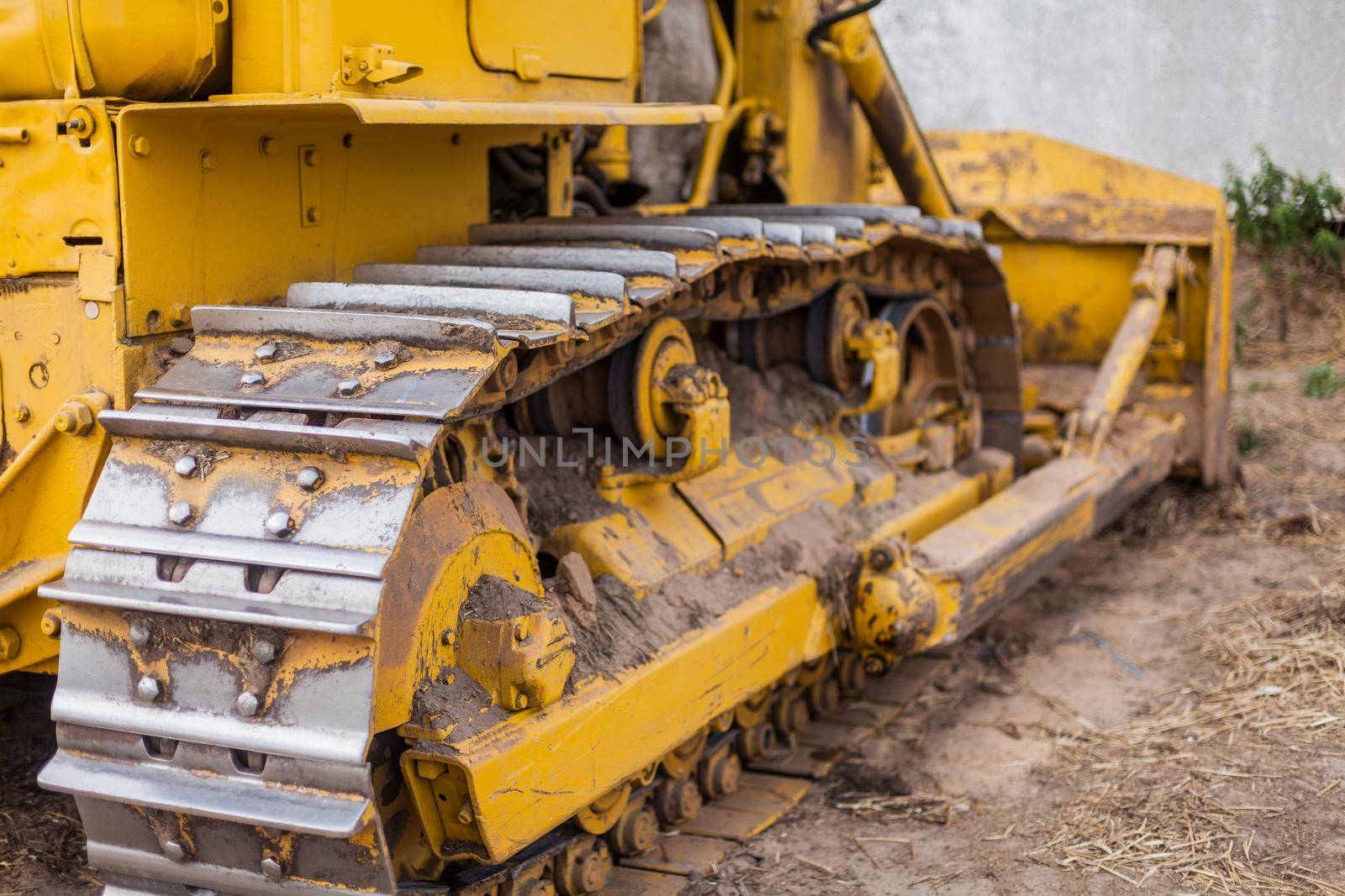 Close-up of crawler bulldozer truck. Earthmoving heavy machinery. Yellow crawler machinery. Yellow Tractor on caterpillar tracks, tractor tracks