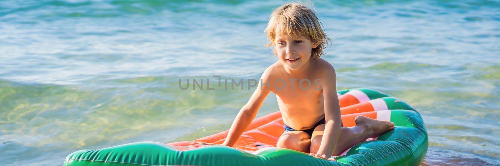 The boy swims in the sea on an inflatable mattress. BANNER, LONG FORMAT