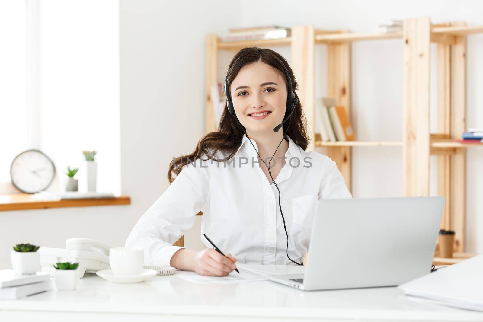 Call Center Concept: Portrait of happy smiling female customer support phone operator at workplace. by Benzoix