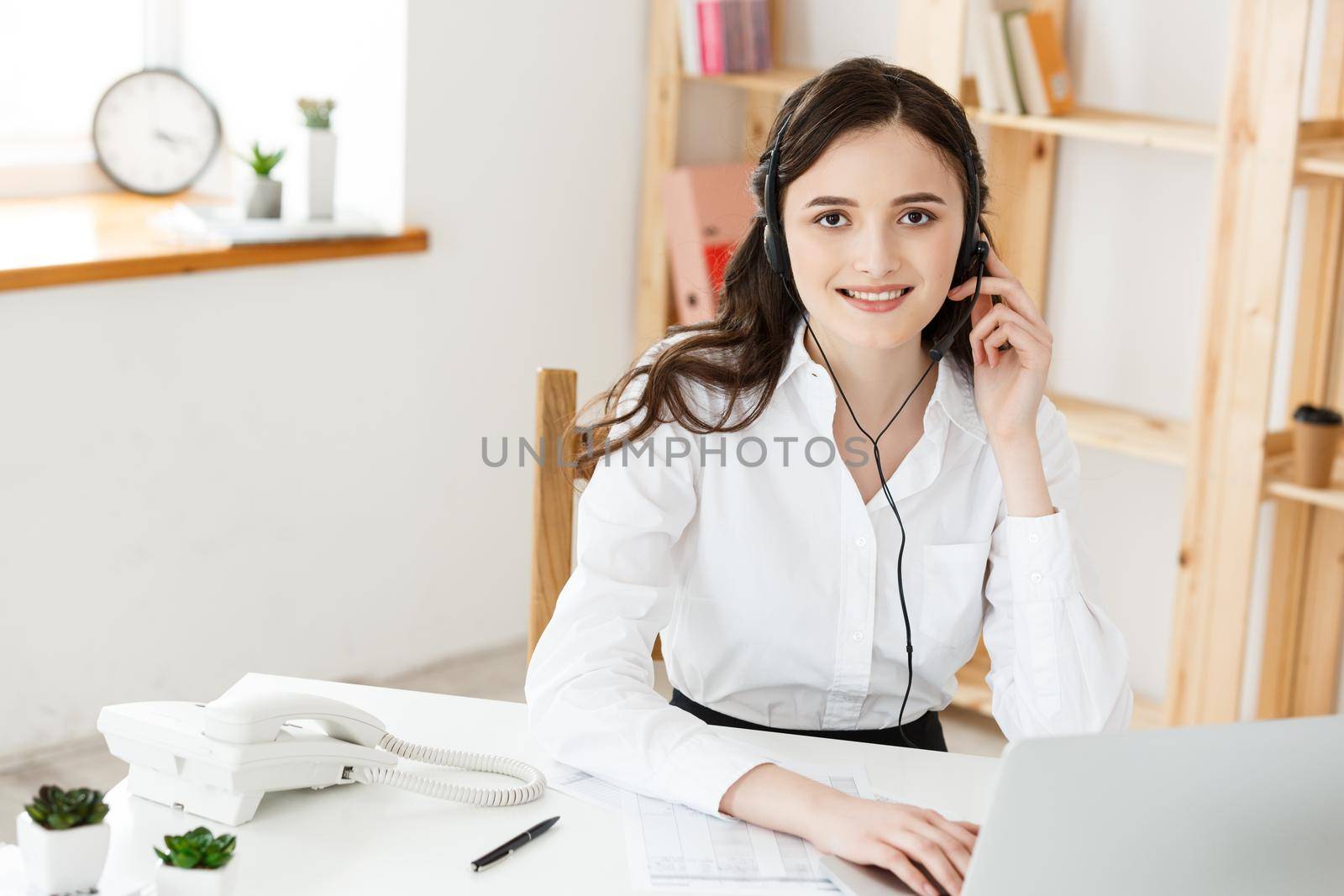 Young friendly operator woman agent or business woman with headsets working in a call centre. by Benzoix