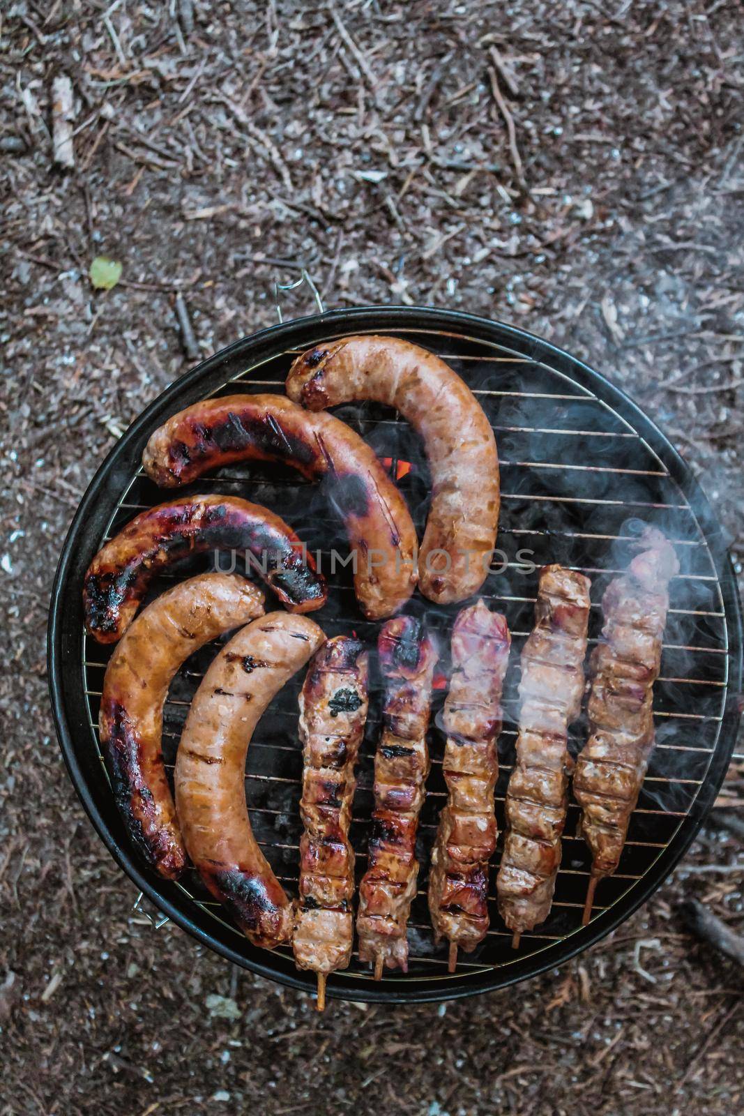 Summer grilling food, sausage, vegetables and kebab meat on barbecue grill over smoke and hot charcoal by JuliaDorian