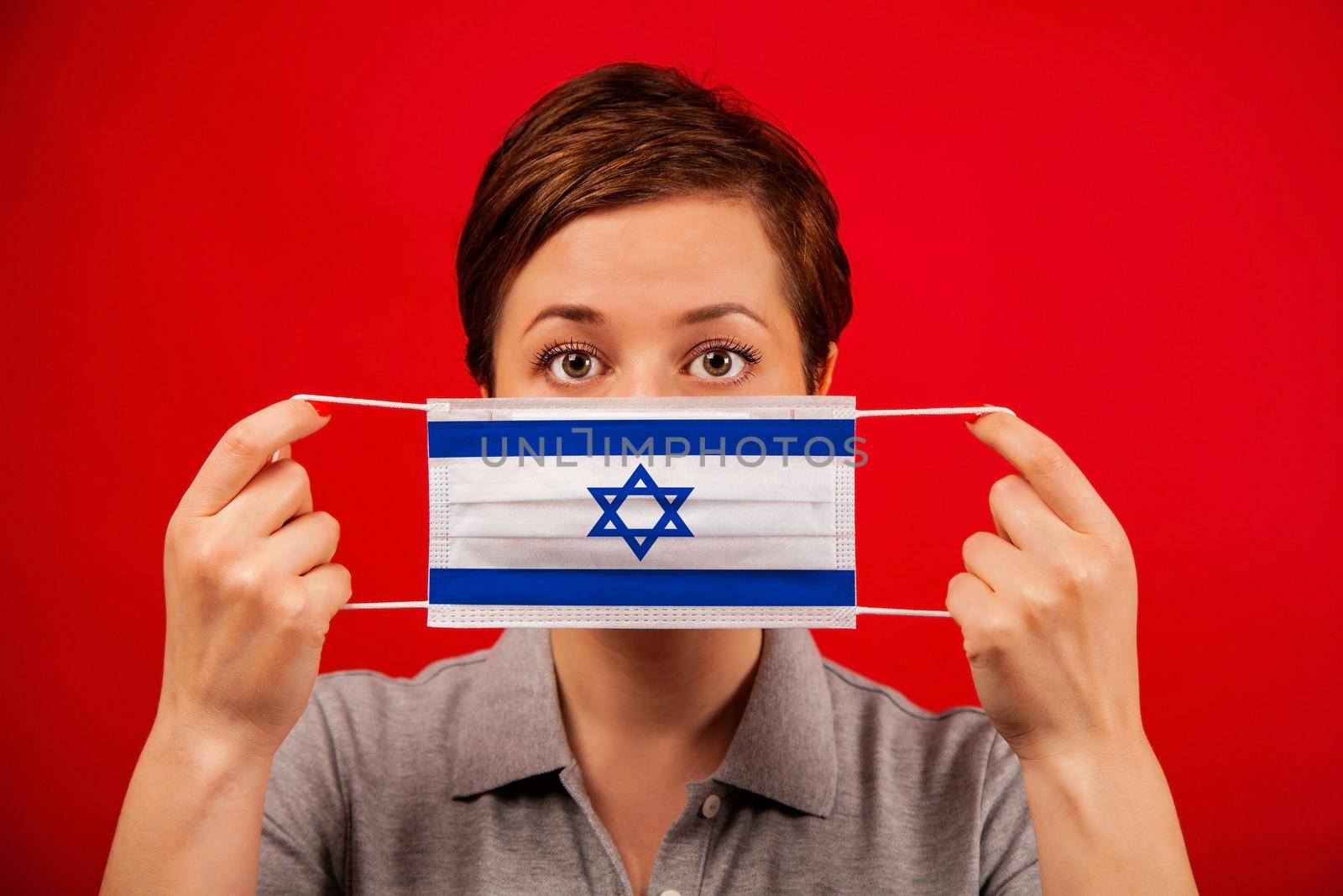 Coronavirus COVID-19 in Israel. Woman in medical protective mask with the image of the flag of Israel. The concept of preventing the spread of the epidemic and treating coronavirus.