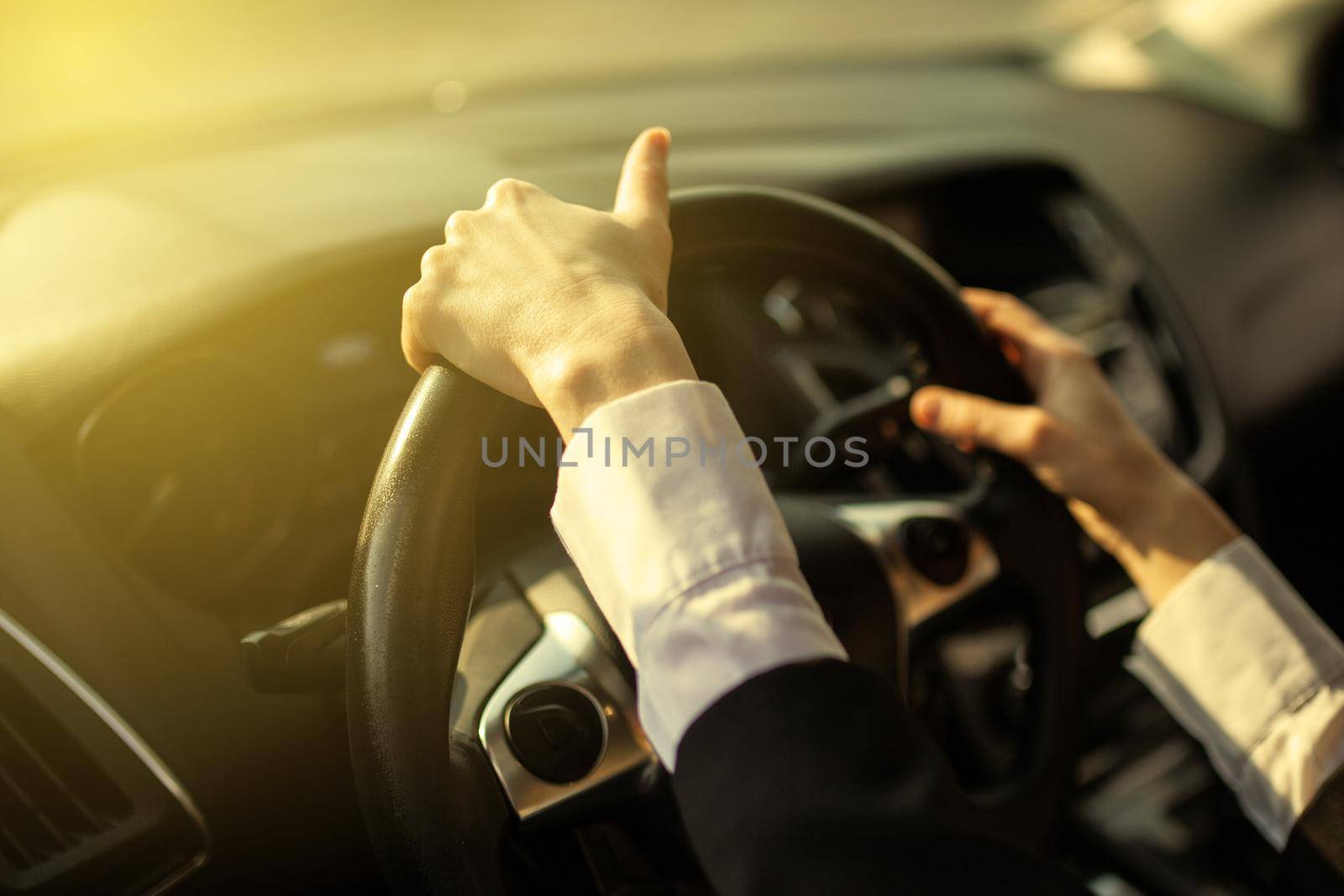 The girl holds her hands behind the wheel of the car.