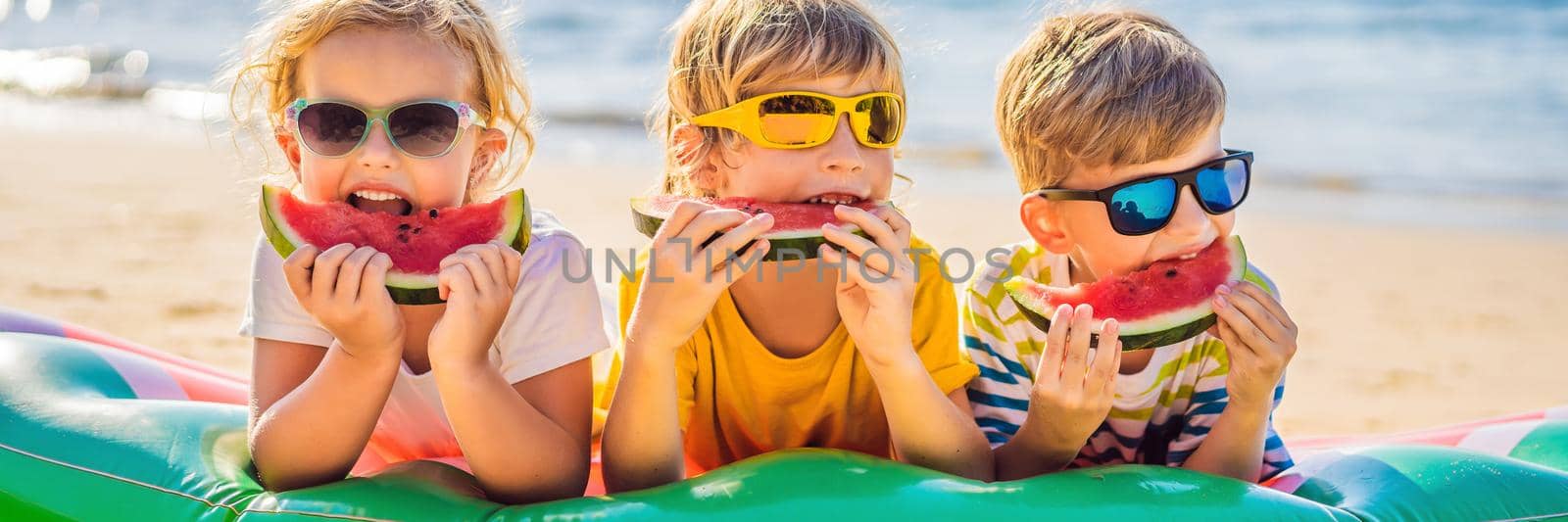 Children eat watermelon on the beach in sunglasses. BANNER, LONG FORMAT