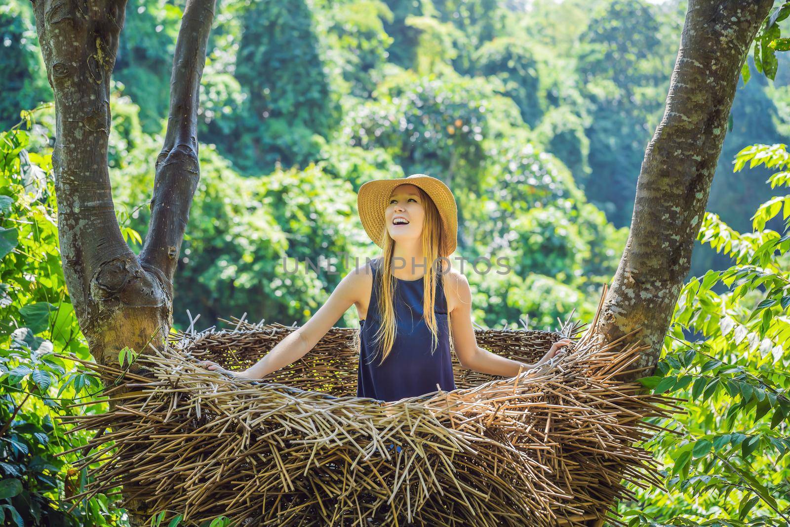 Bali trend, straw nests everywhere. Young tourist enjoying her travel around Bali island, Indonesia. Making a stop on a beautiful hill. Photo in a straw nest, natural environment. Lifestyle.