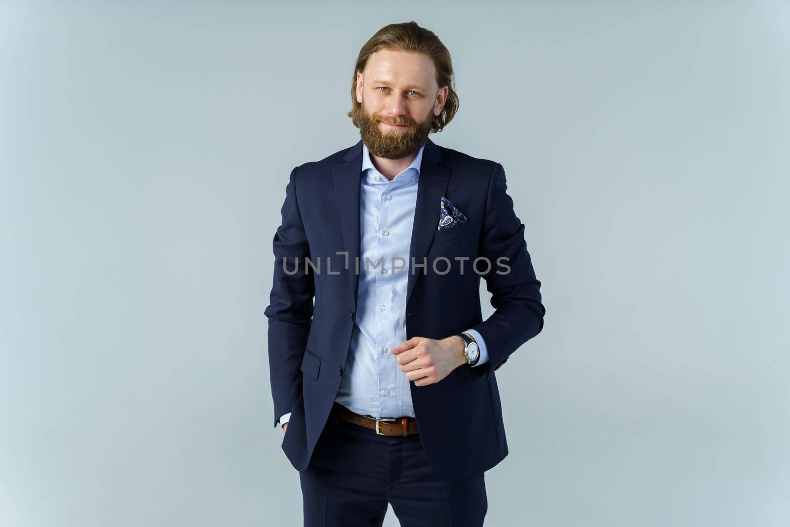 a handsome brutal bearded and long-haired man, a stylish businessman on a white background. High quality photo