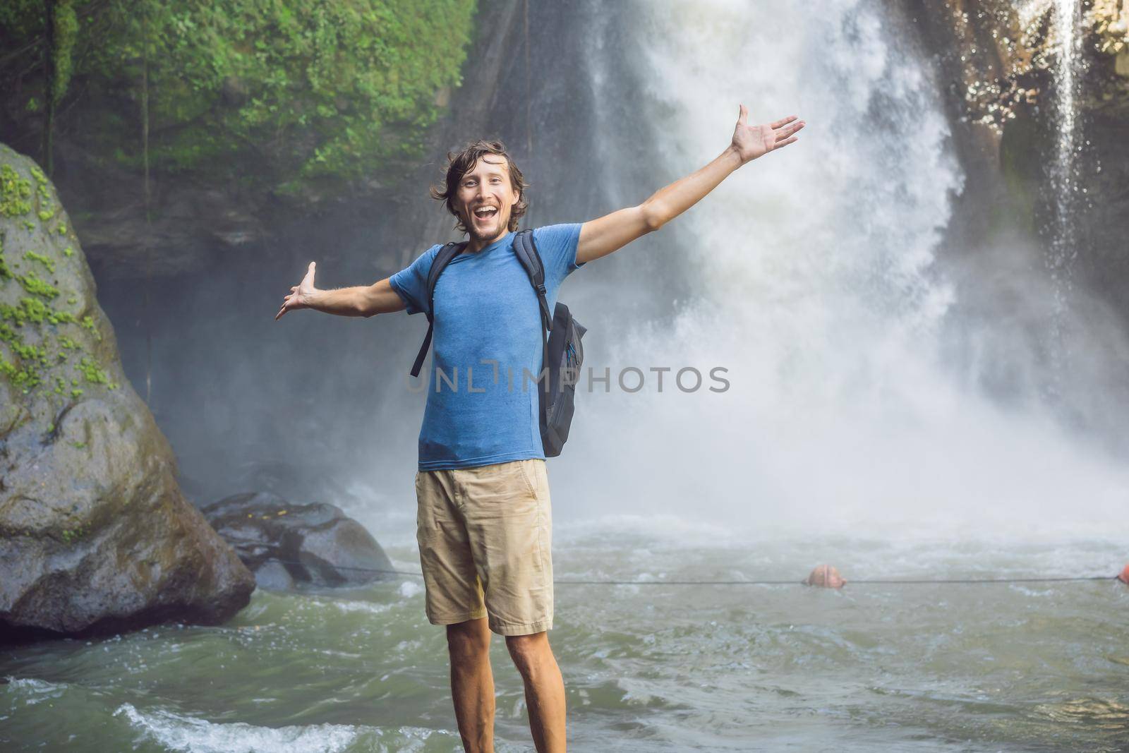 Man traveler on a waterfall background. Ecotourism concept.
