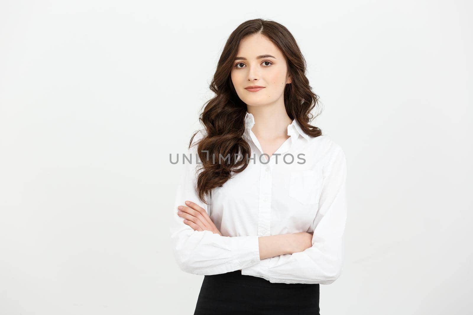 Business Concept: Portrait confident young businesswoman keeping arms crossed and looking at camera while standing against grey background.