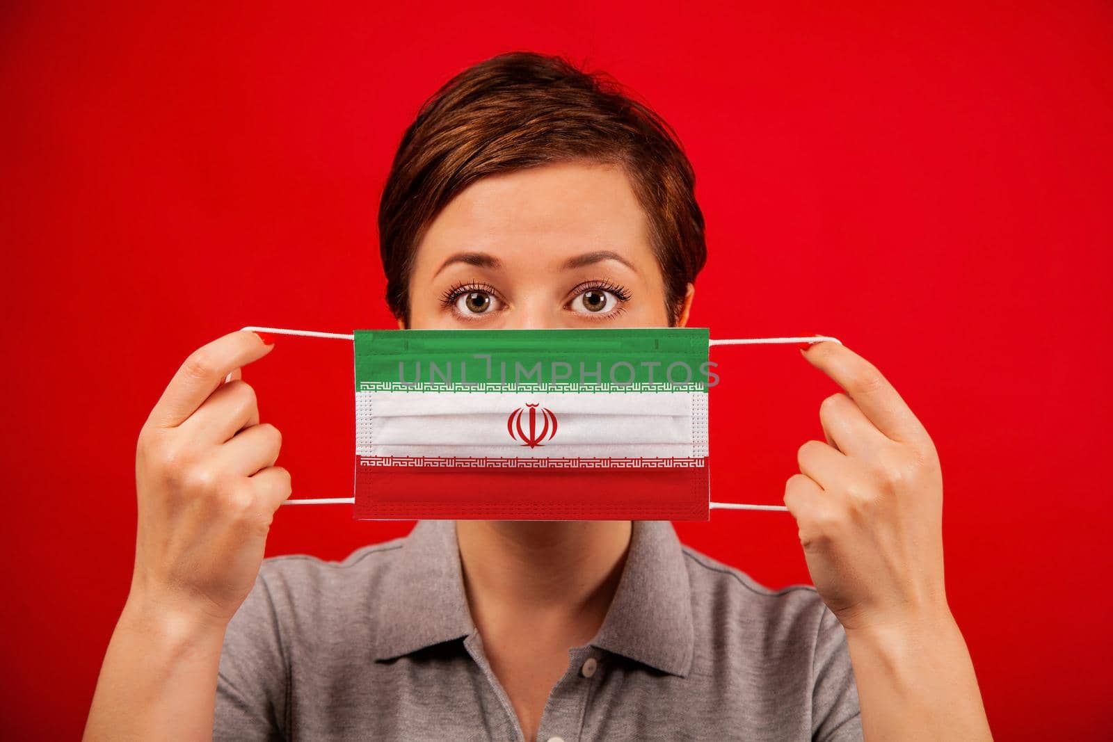 Coronavirus COVID-19 in Iran. Woman in medical protective mask with the image of the flag of Iran. The concept of preventing the spread of the epidemic and treating coronavirus.