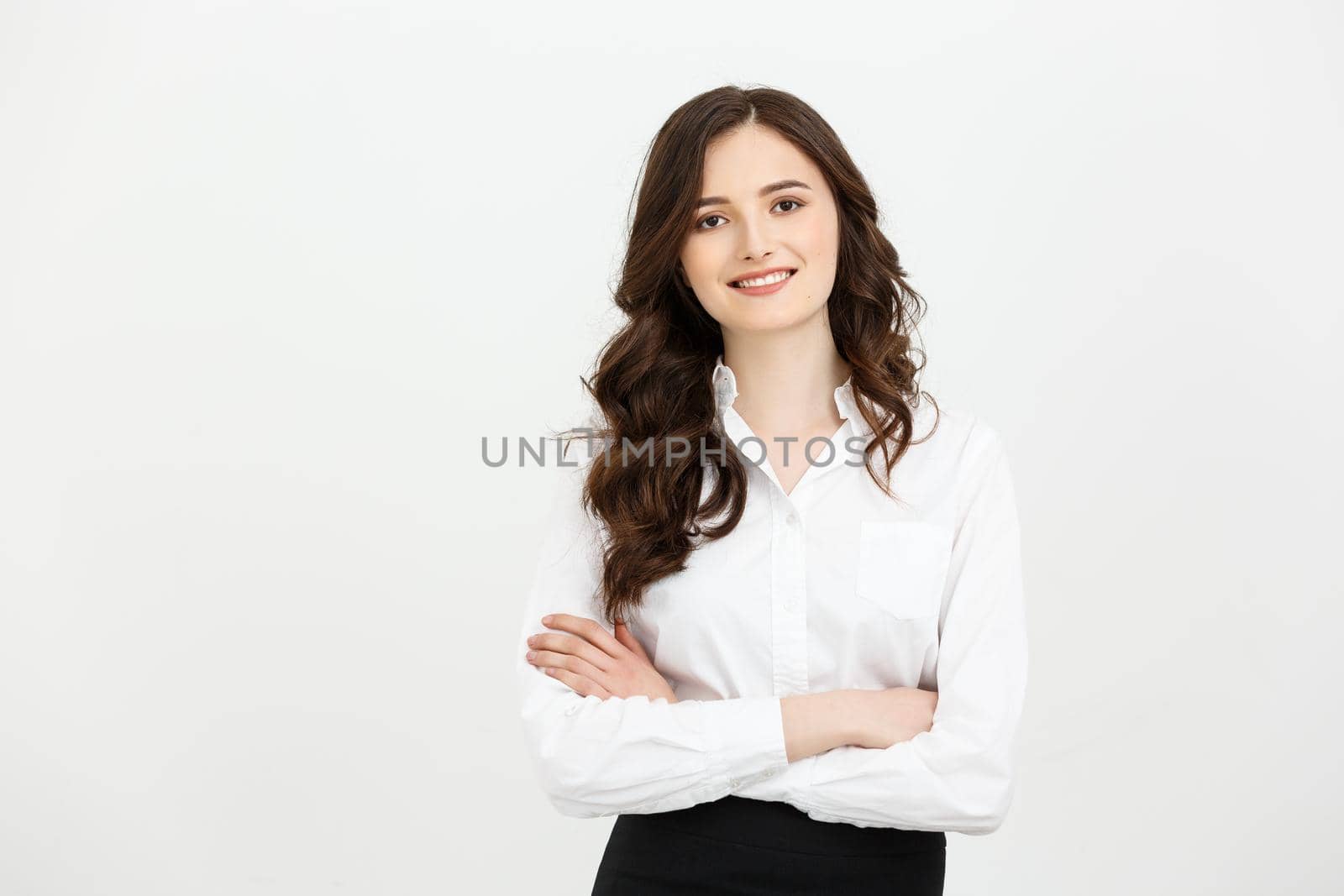 Business Concept: Portrait confident young businesswoman keeping arms crossed and looking at camera while standing against grey background.