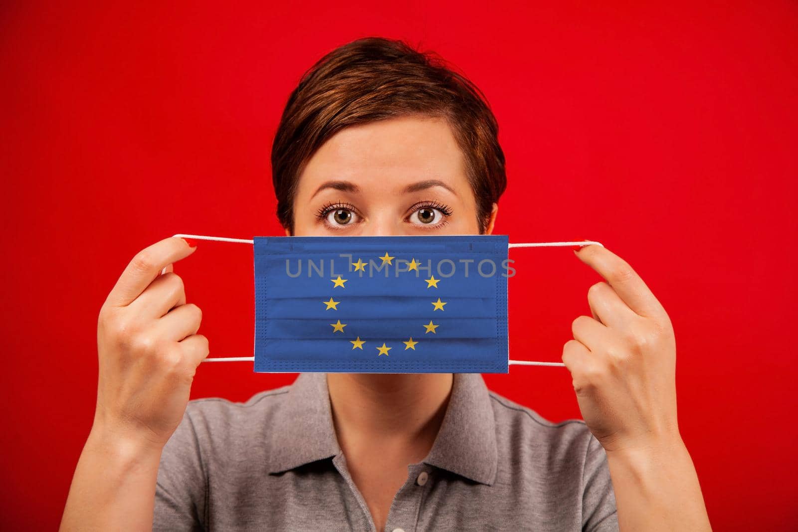 Coronavirus COVID-19 in Europe. Woman in medical protective mask with the image of the flag of Europe. The concept of preventing the spread of the epidemic and treating coronavirus.
