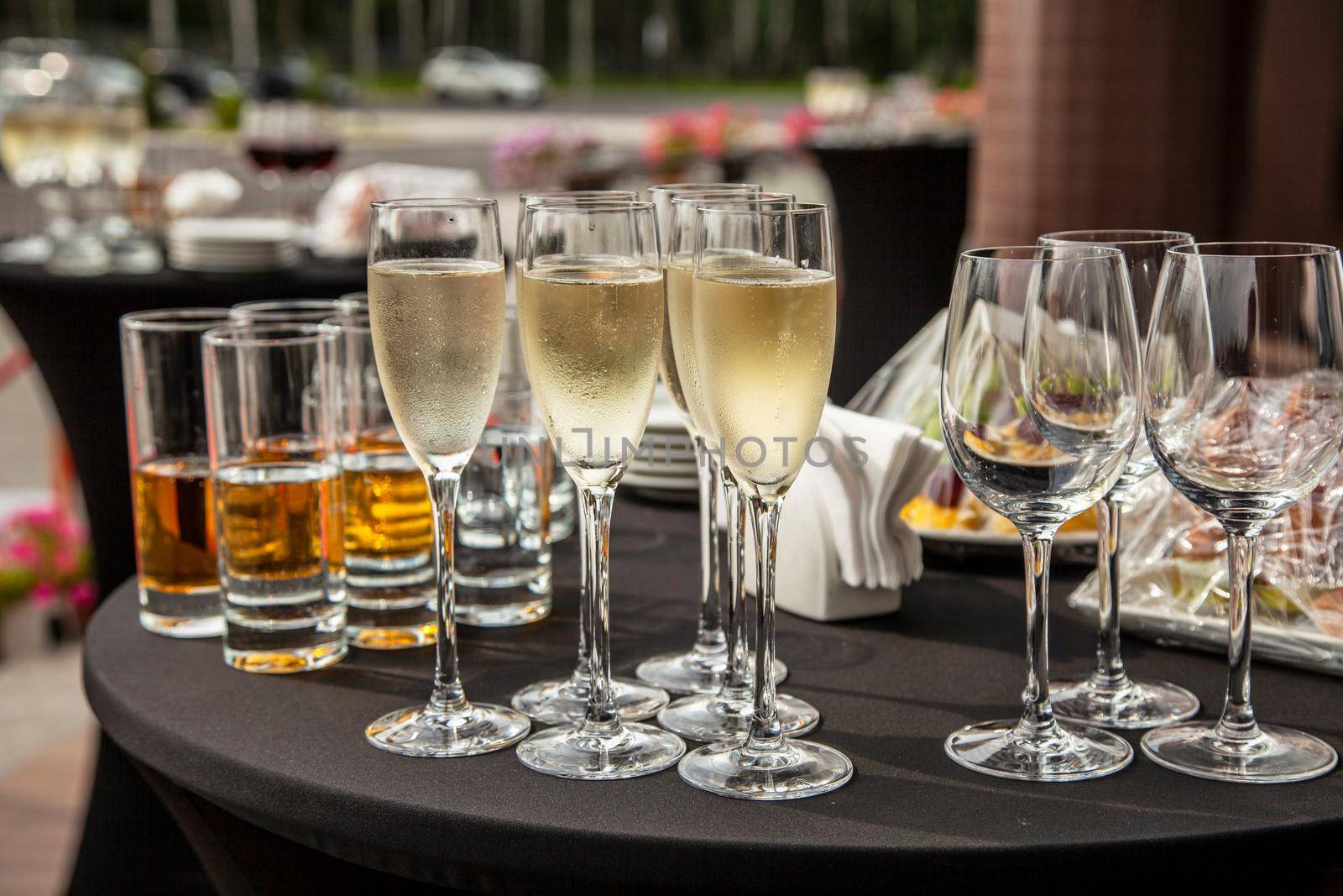 A buffet table on the terrace with glasses of champagne. Glasses with champagne and empty wine glasses are on the terrace table.