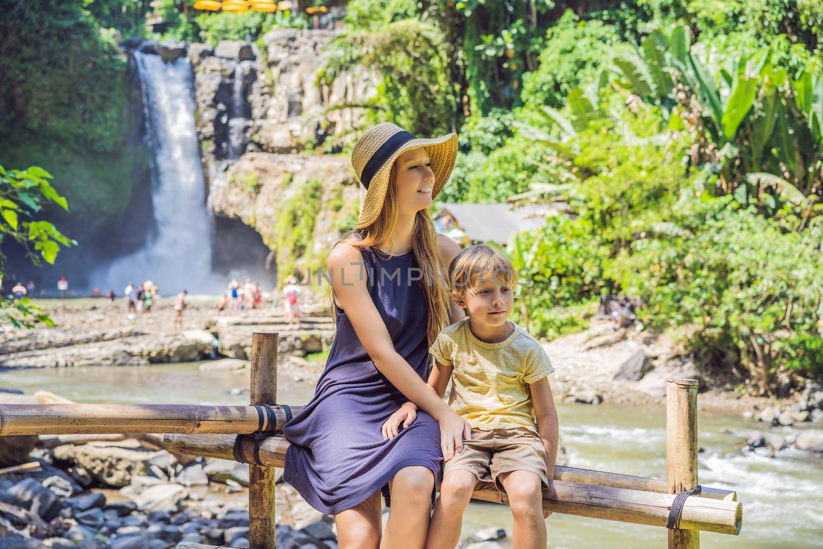 Mom and son tourists on the background of a waterfall. Traveling with kids concept. What to do with children Children friendly place.