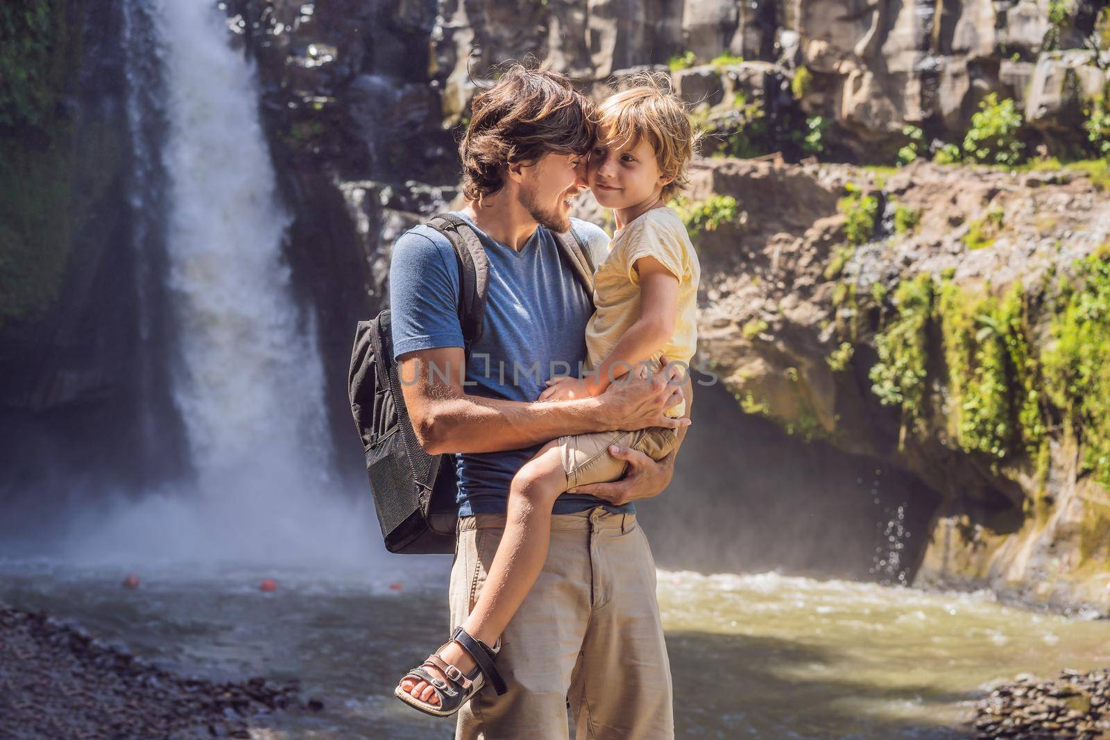 Dad and son tourists on the background of a waterfall. Traveling with kids concept. What to do with children Children friendly place.