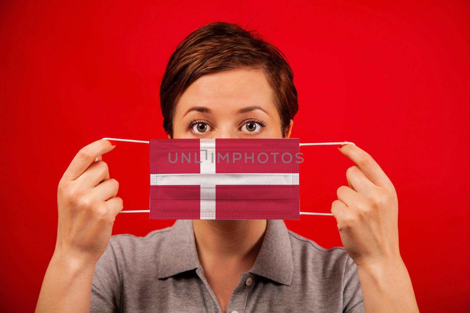Coronavirus COVID-19 in Denmark. Woman in medical protective mask with the image of the flag of Denmark. The concept of preventing the spread of the epidemic and treating coronavirus.