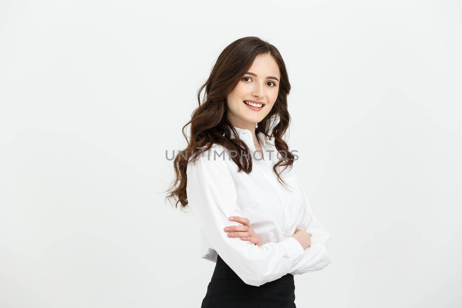 Business Concept: Portrait confident young businesswoman keeping arms crossed and looking at camera while standing against grey background.