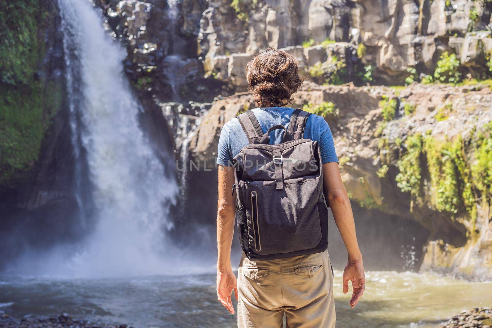 Man traveler on a waterfall background. Ecotourism concept.