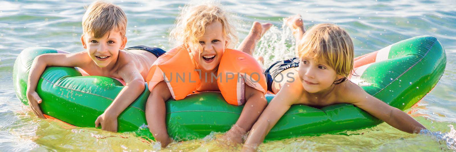 Children swim in the sea on an inflatable mattress and have fun. BANNER, LONG FORMAT