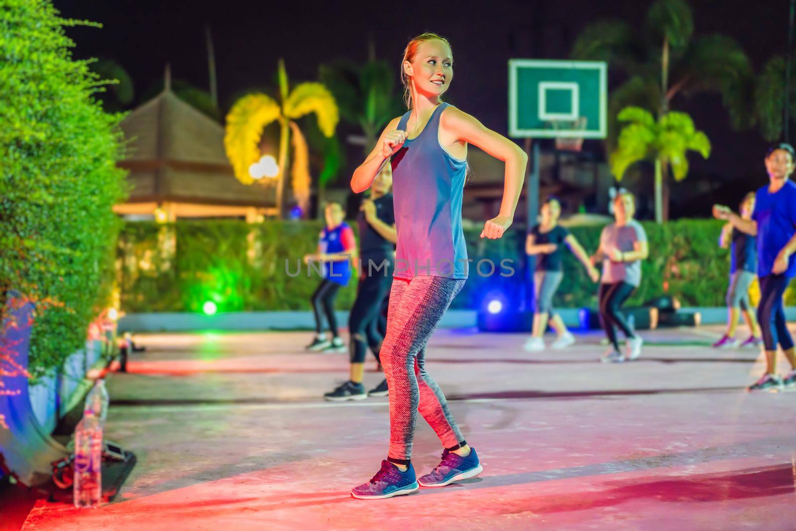 Young woman on a group workout on the basketball court in the evening.