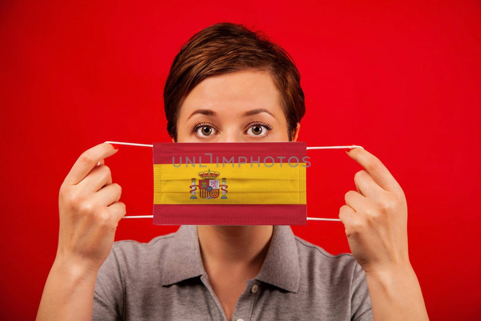 Coronavirus COVID-19 in Spain. Woman in medical protective mask with the image of the flag of Spain. The concept of preventing the spread of the epidemic and treating coronavirus.