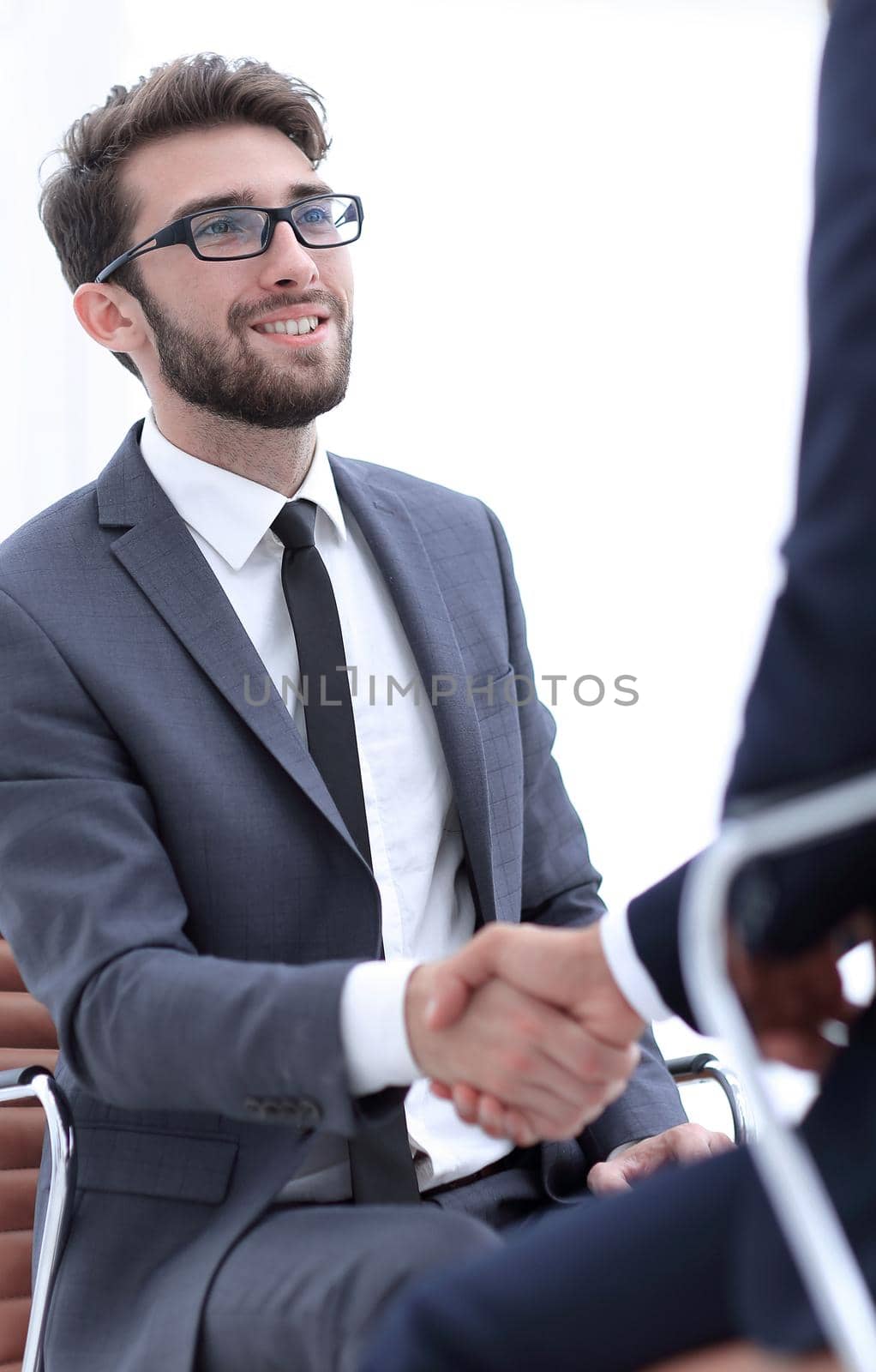 Image of two young businessmen interacting at meeting in office