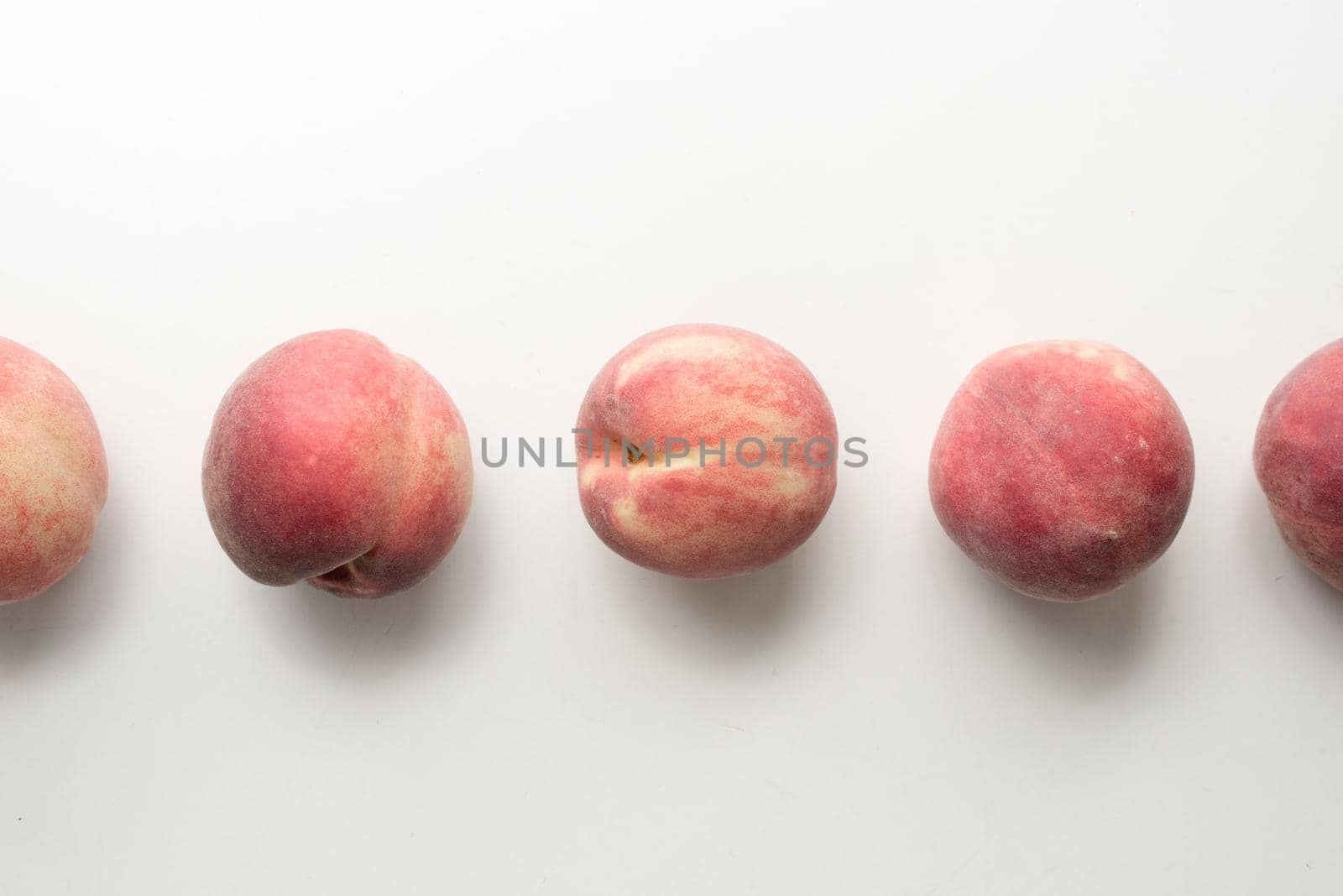 High angle view of five white peaches arranged in a row on table