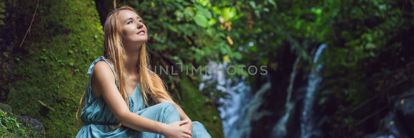 Woman traveler on a waterfall background. Ecotourism concept. BANNER, LONG FORMAT