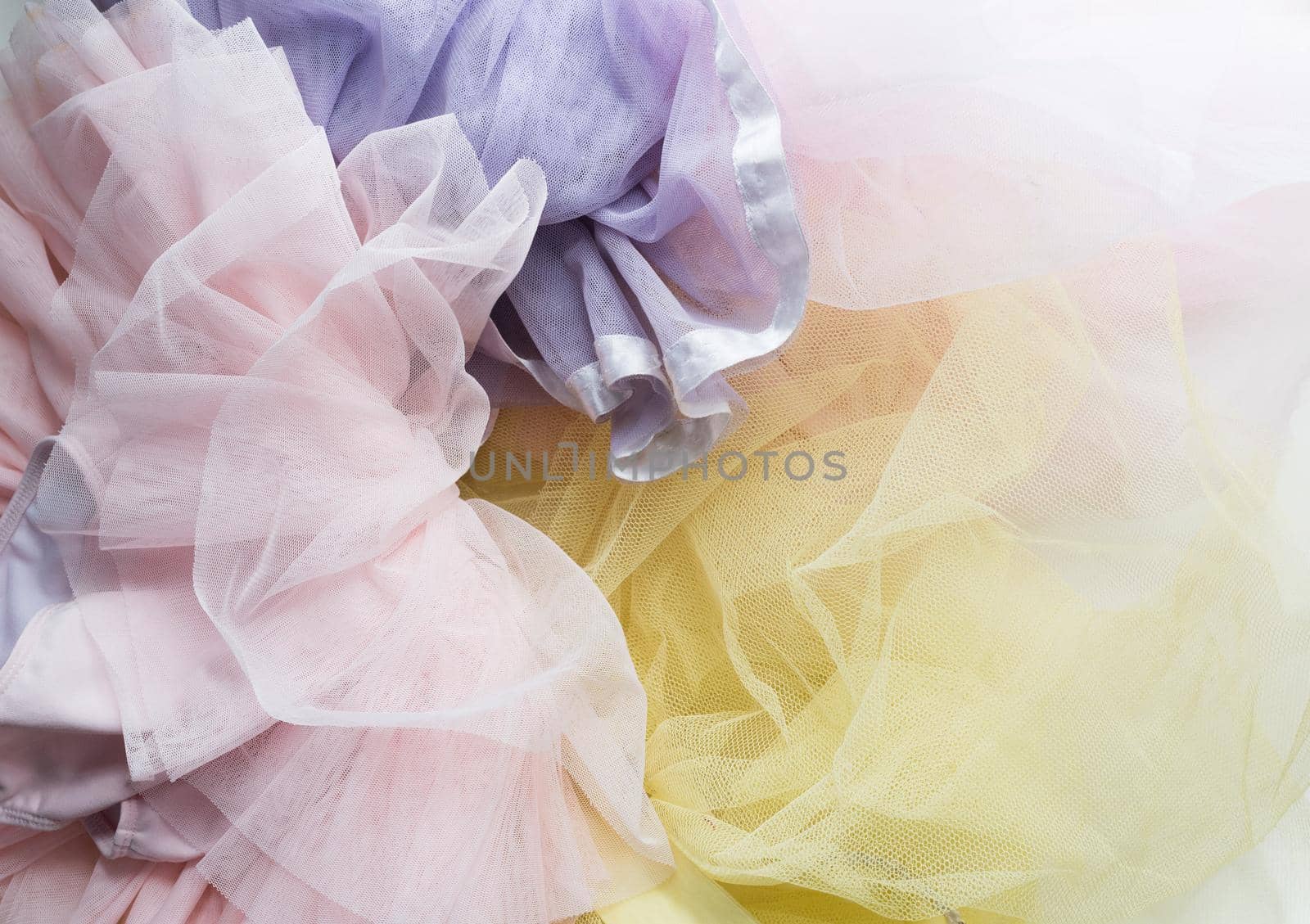 High angle full frame view of little girl's pink, purple and yellow tutus in a pile
