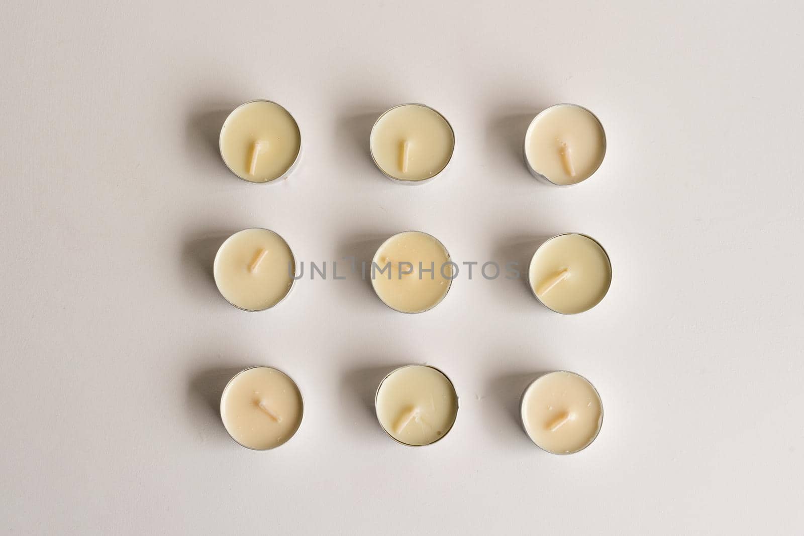 High angle view of unlit tealights arranged on white table