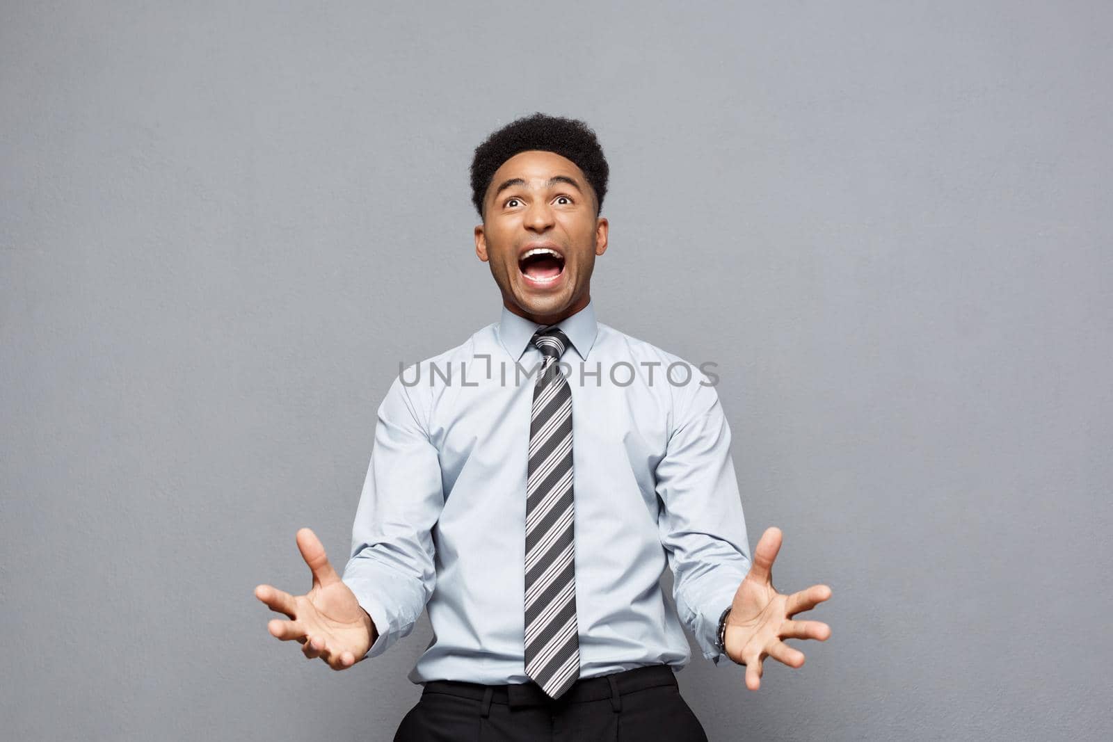 Business Concept - Confident cheerful young African American showing hands in front of him with disappointed expression over grey background