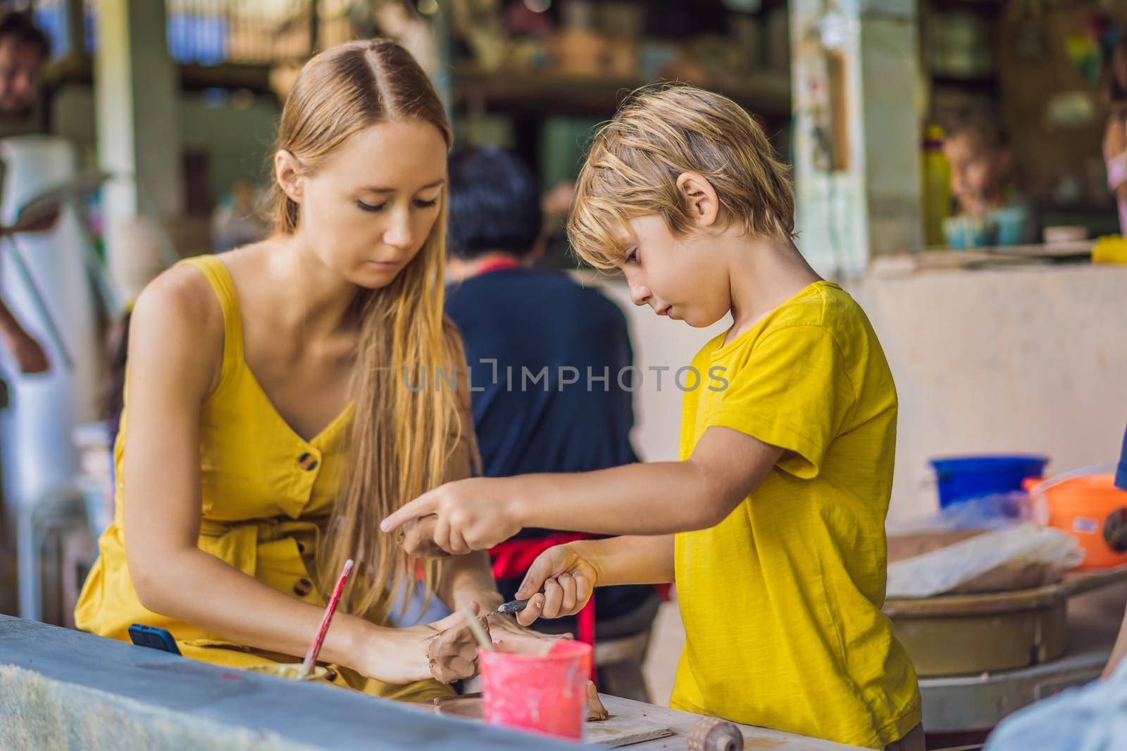 mother and son doing ceramic pot in pottery workshop. What to do with children. Child friendly place.