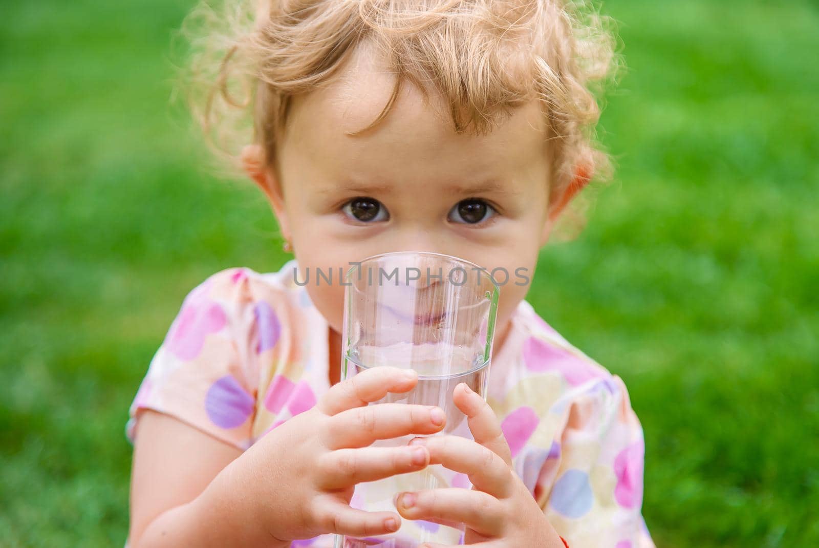 Baby drinks water from a glass. Selective focus. Child.