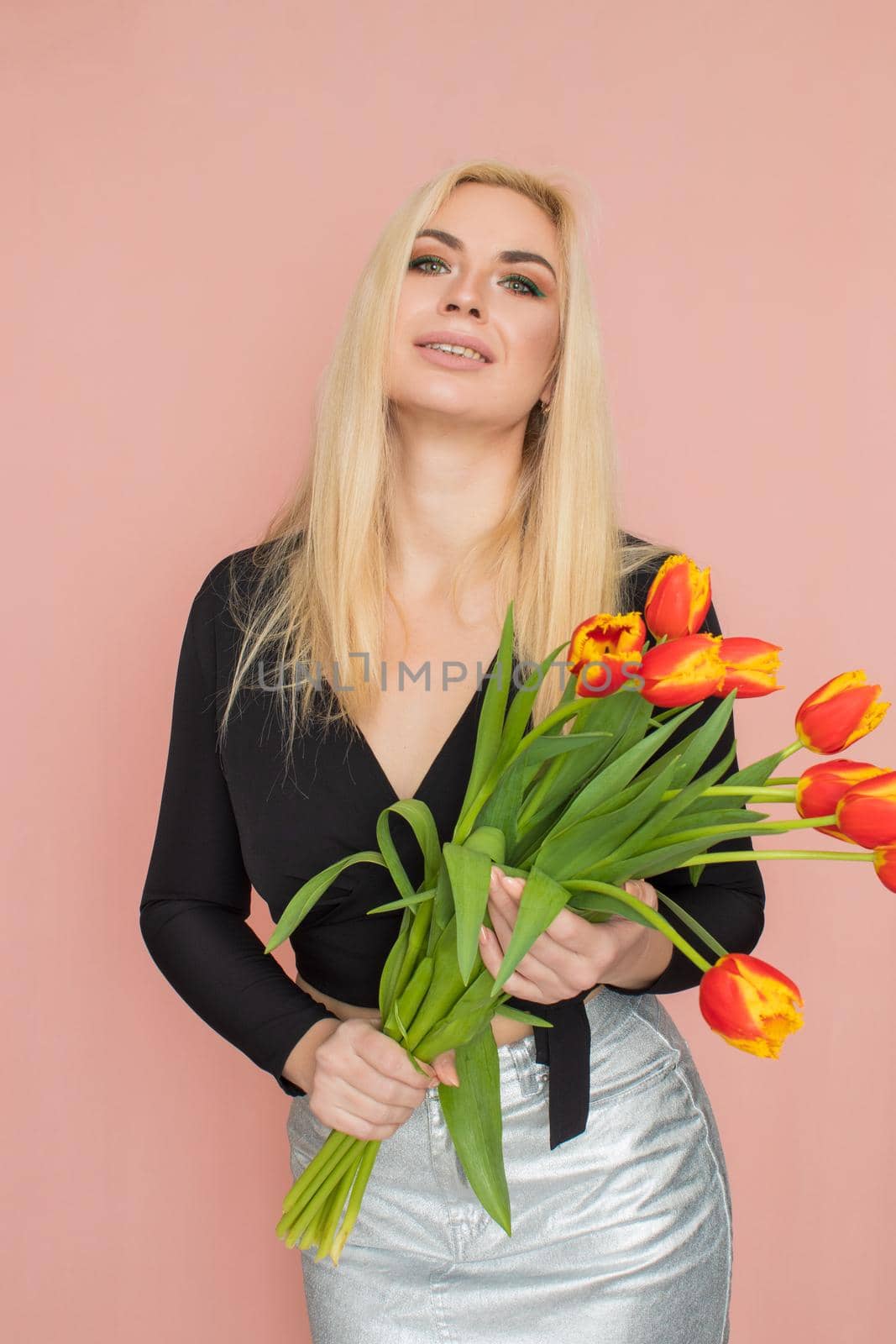 Fashion blonde woman holding red tulips in her hands by Bonda