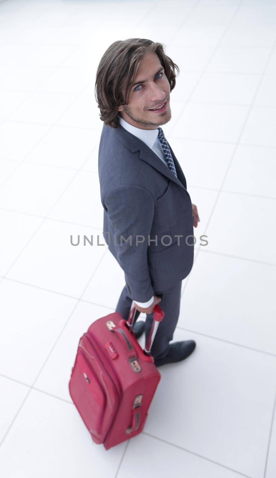 side view.smiling businesswoman with travel suitcase looking at the camera .photo with copy space