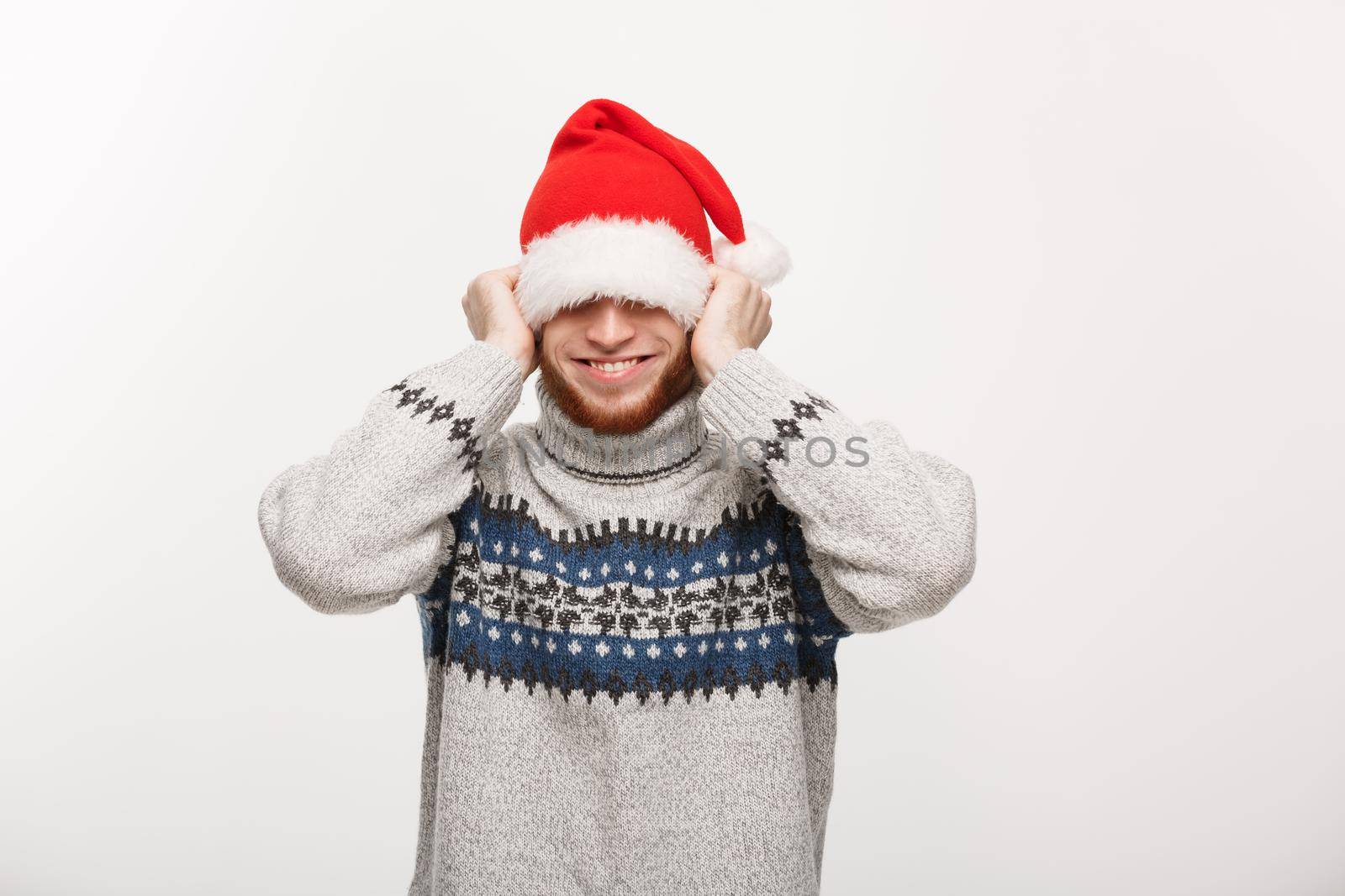Holiday Concept - Young beard man in sweater enjoy playing with santa hat.