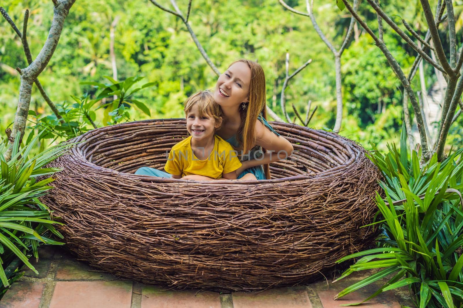 Bali trend, straw nests everywhere. Happy family enjoying their travel around Bali island, Indonesia. Making a stop on a beautiful hill. Photo in a straw nest, natural environment. Lifestyle. Traveling with kids concept. What to do with children. Child friendly place by galitskaya