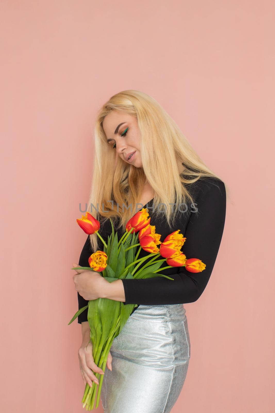 Fashion blonde woman holding red tulips in her hands by Bonda