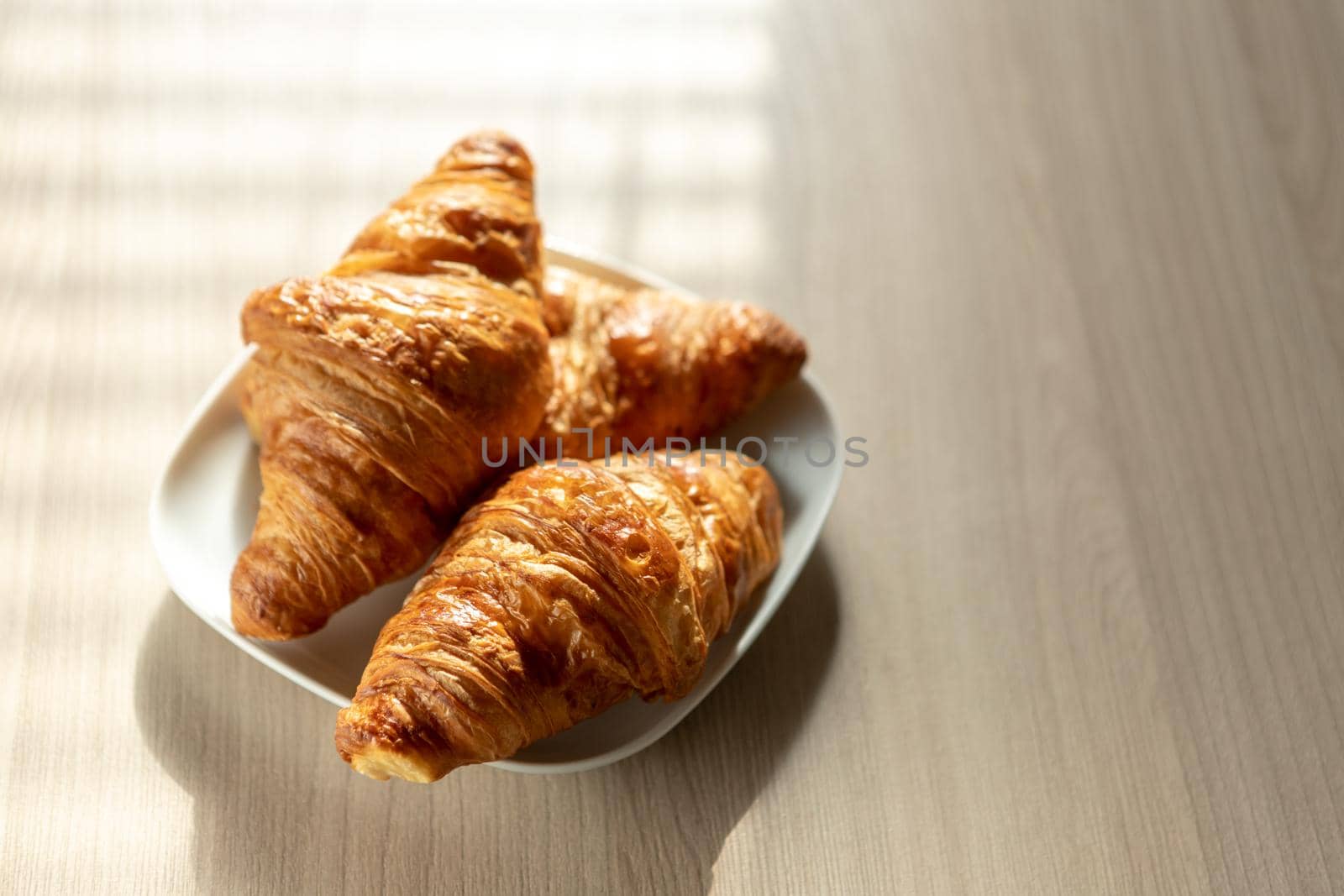 there are three crispy croissants on a white breakfast plate on the table