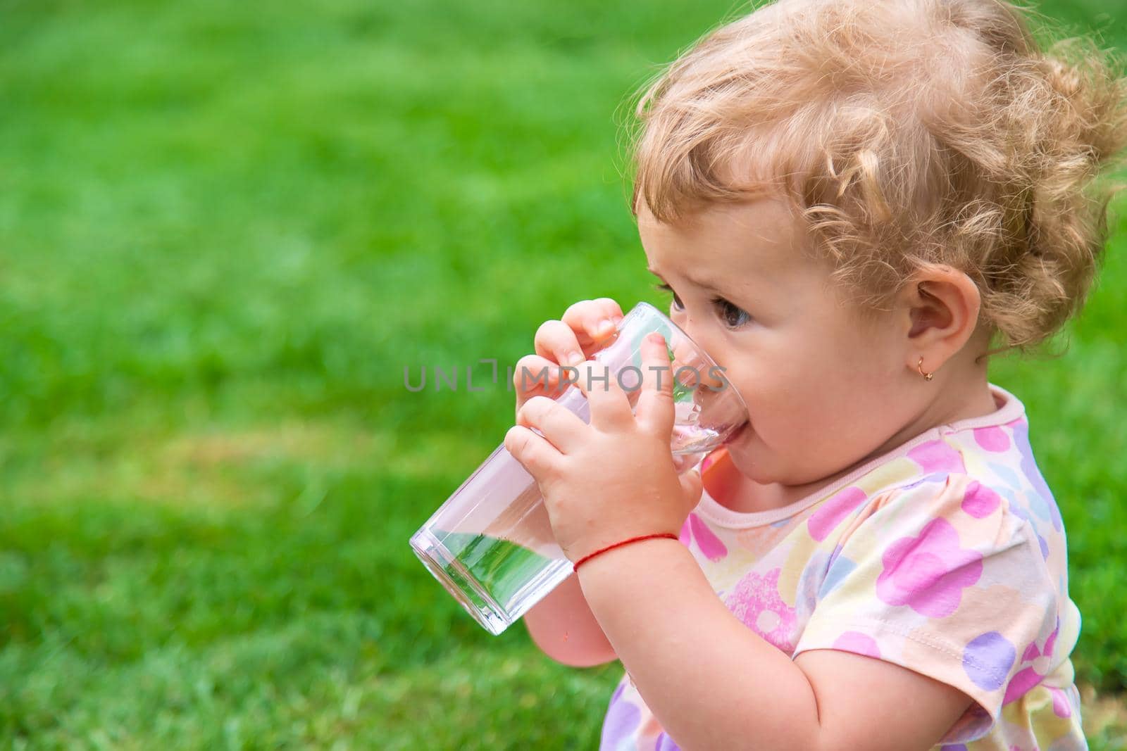 Baby drinks water from a glass. Selective focus. Child.