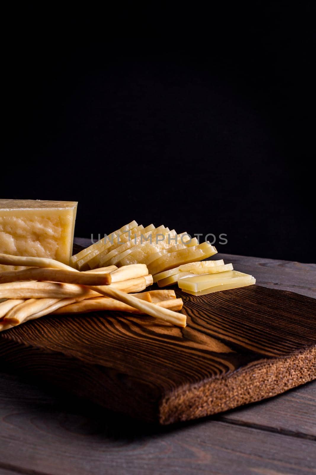 hard cheese and fibrous cheese with slices of bread on a wooden board by bySergPo