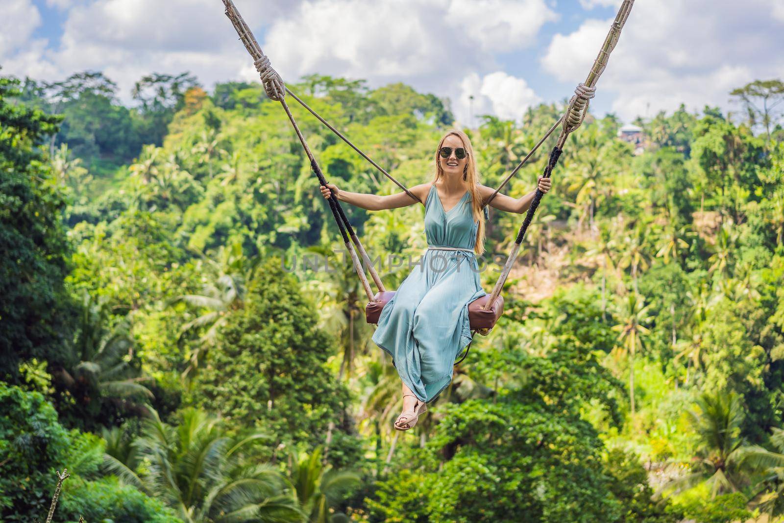 Young woman swinging in the jungle rainforest of Bali island, Indonesia. Swing in the tropics. Swings - trend of Bali.