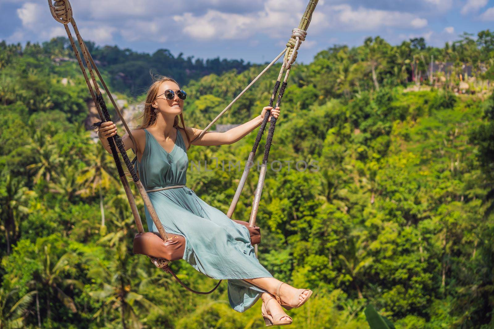 Young woman swinging in the jungle rainforest of Bali island, Indonesia. Swing in the tropics. Swings - trend of Bali.