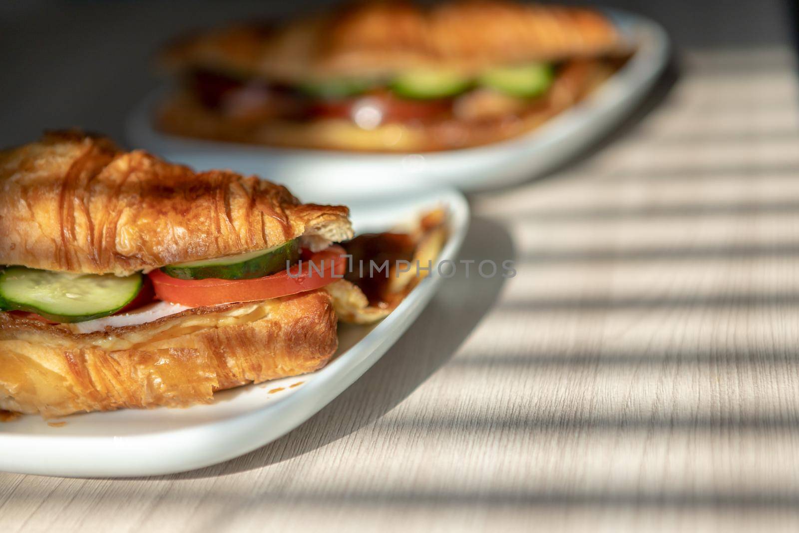 fresh croissants stuffed with omelet carbonade and fresh vegetables with cheese for breakfast under the sunlight