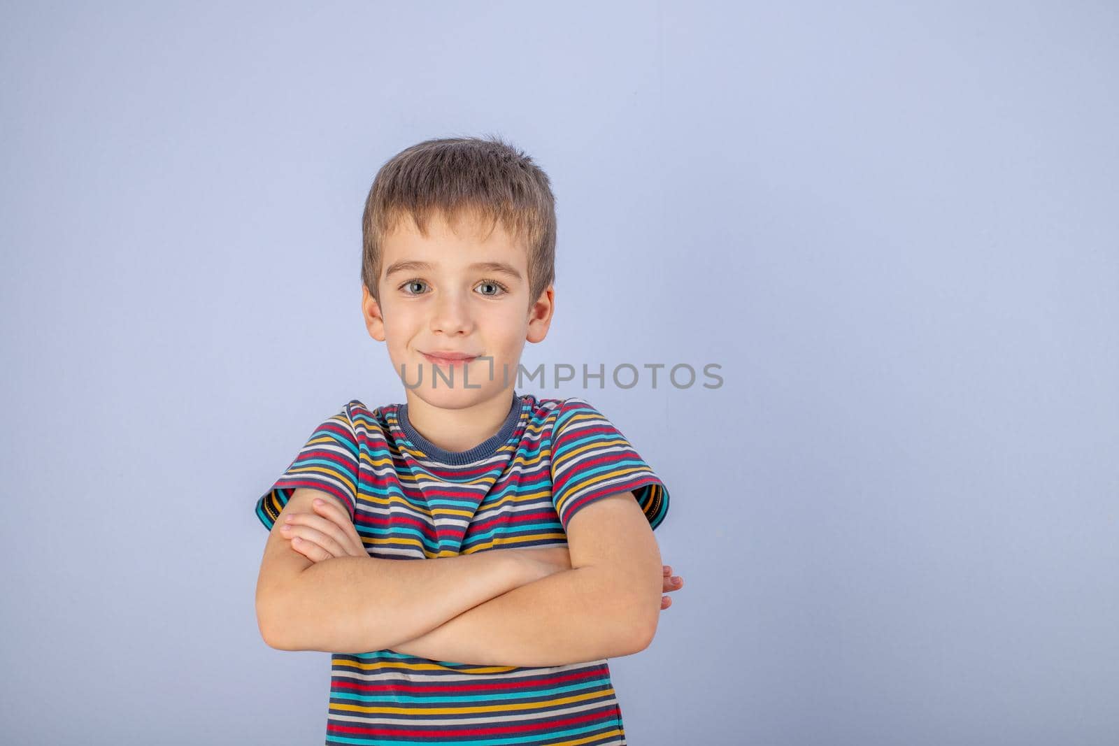 A little boy dressed in a multicolored striped T-shirt. Portrait of a beautiful teenage boy of early age. The pose of a happy smile.