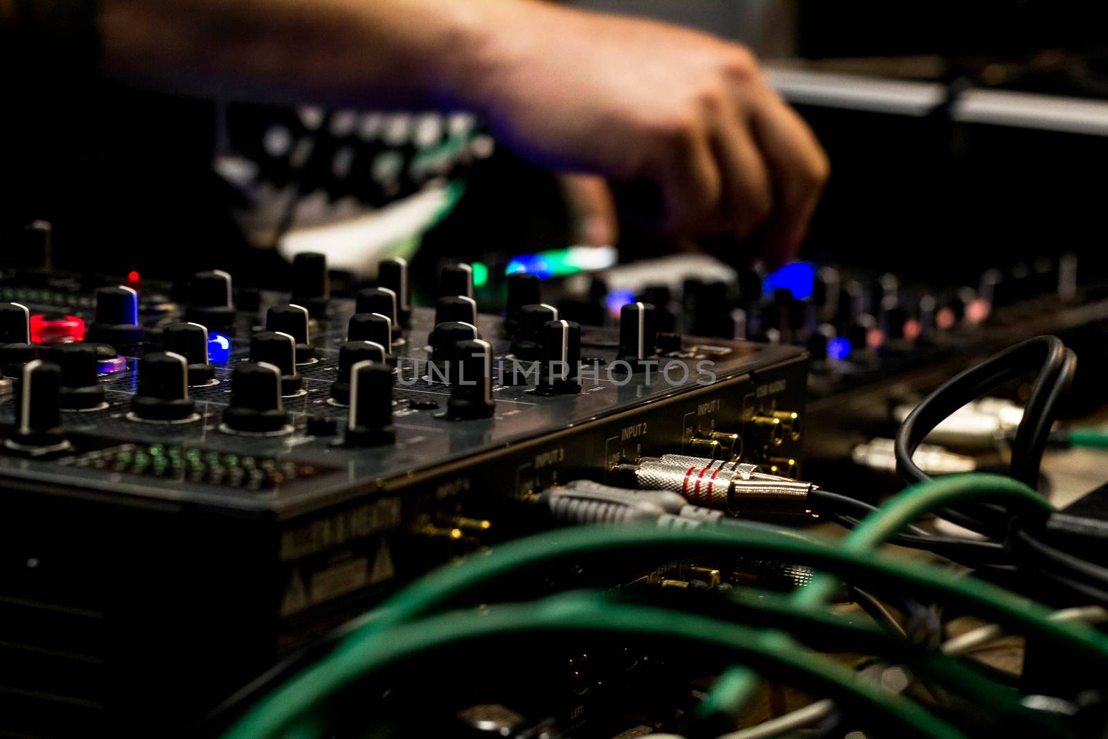 The dj uses the mixer to create electronic music live.