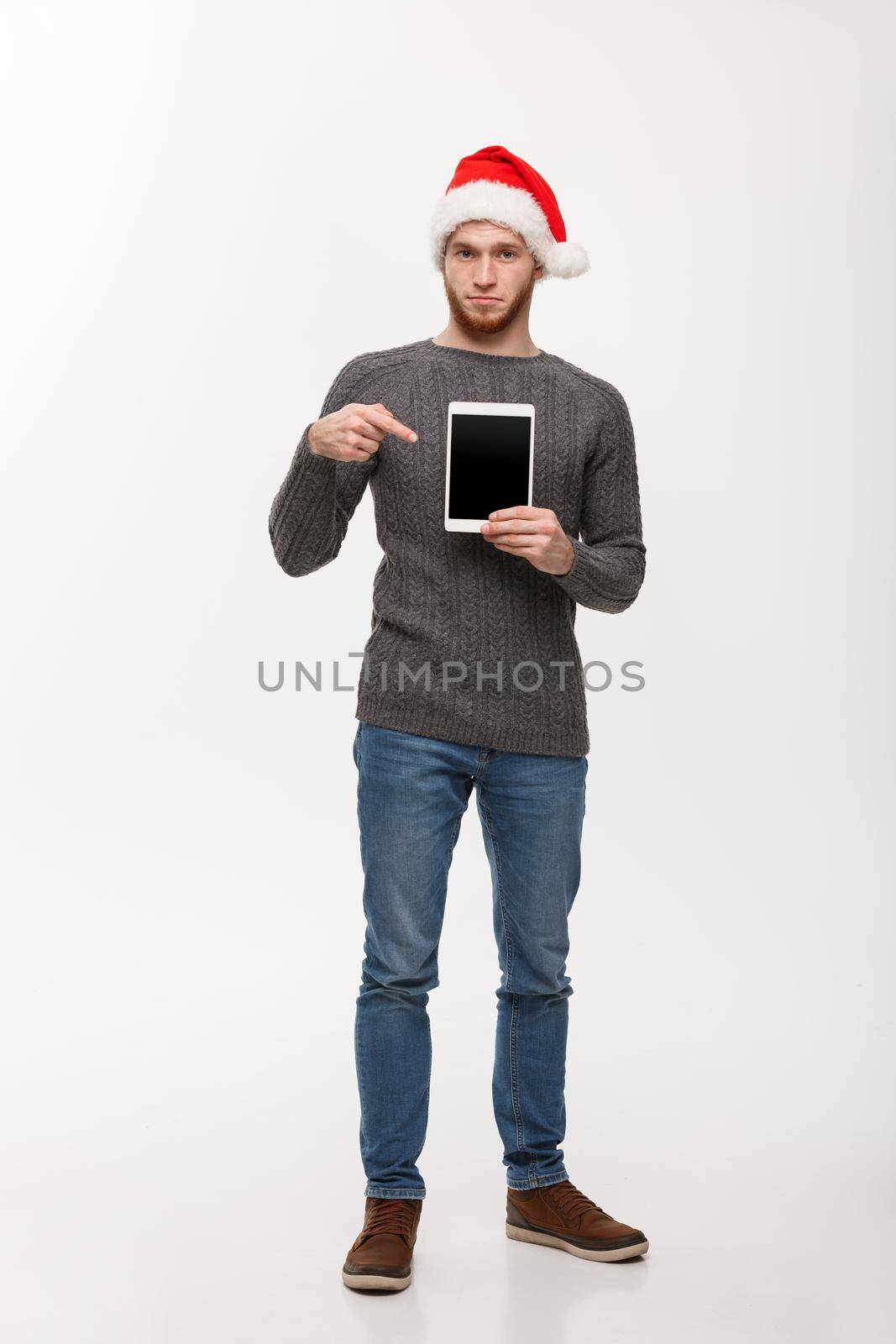 Holiday and Business Concept - Young handsome man showing tablet display and pointing finger presenting. by Benzoix